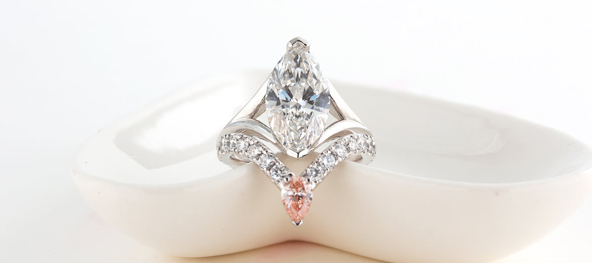A 3ct pear-cut diamond ring crafted in 18K white gold  accented by small diamonds and a pink pear-cut diamond 